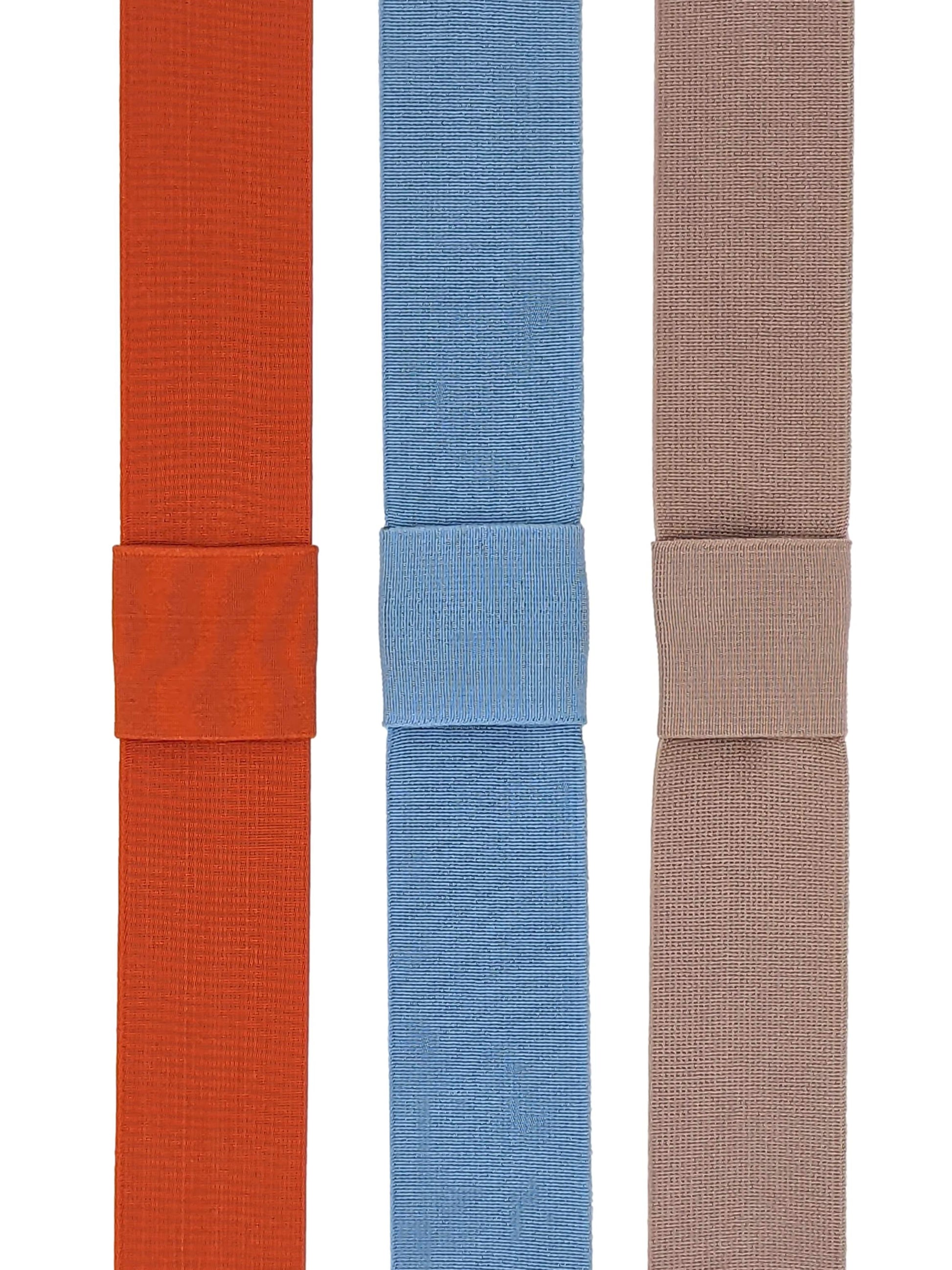 Three elasticated hat bands in orange, sky blue, and oyster colors, displayed side by side.