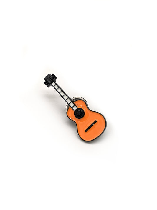 A decorative guitar-shaped brooch in orange, with black details and a rubber backing, designed to pin onto a hat.